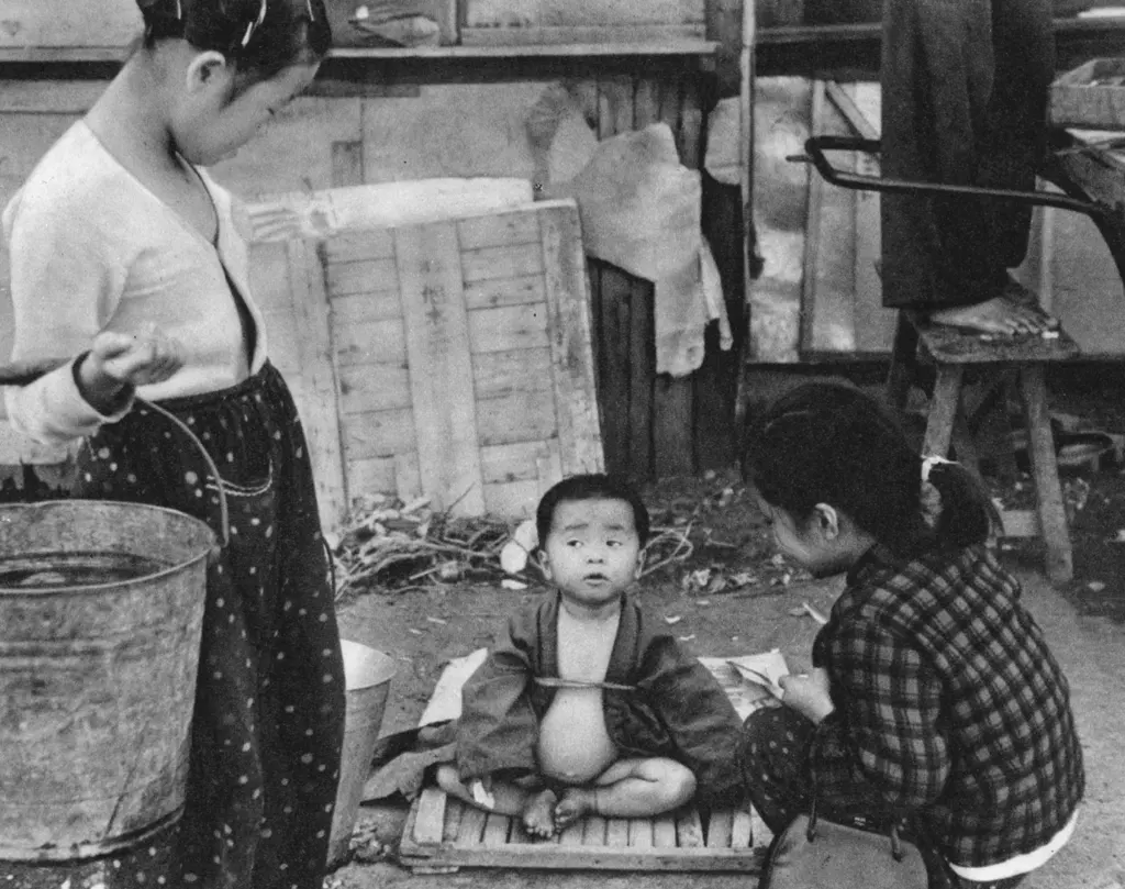 「食べすぎた子 （日の出町界隈の子供）」 船越成江&nbsp;-&nbsp;日本カメラ 1956年2月号より